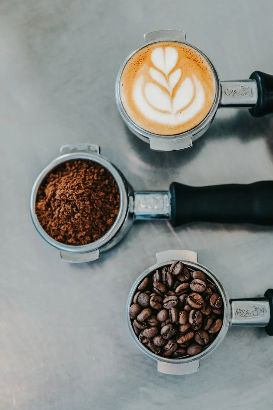 Three portafilters with beans, grounds and a latte